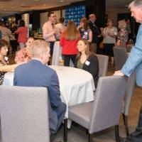 tom standing by a table of attendees